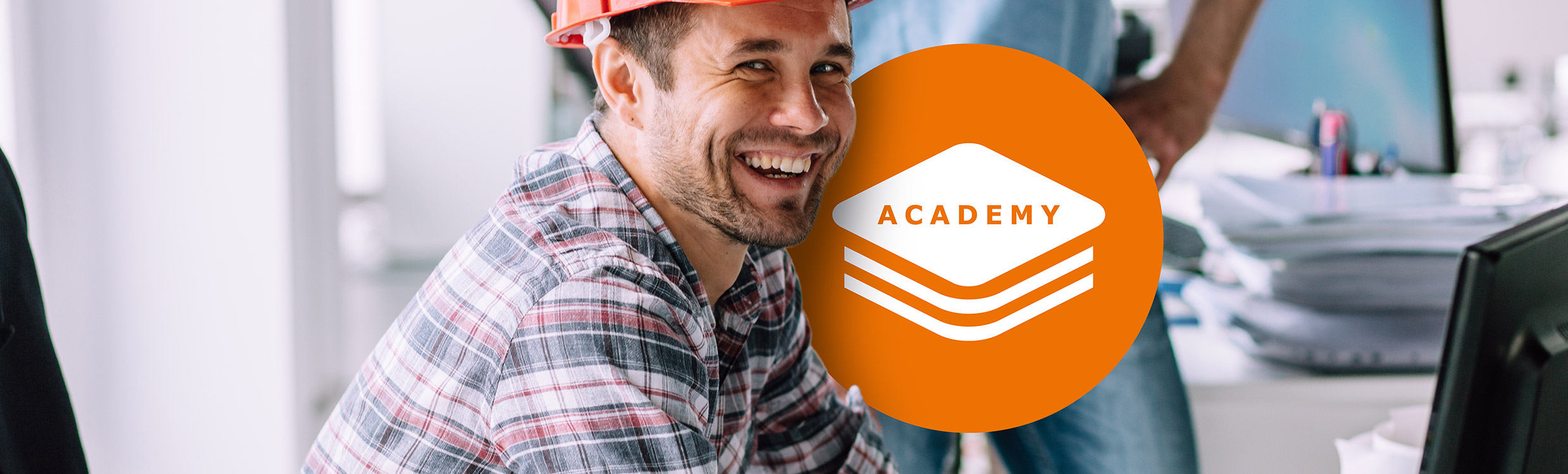 Construction worker working on a laptop with the GeoMax Academy icon on screen
